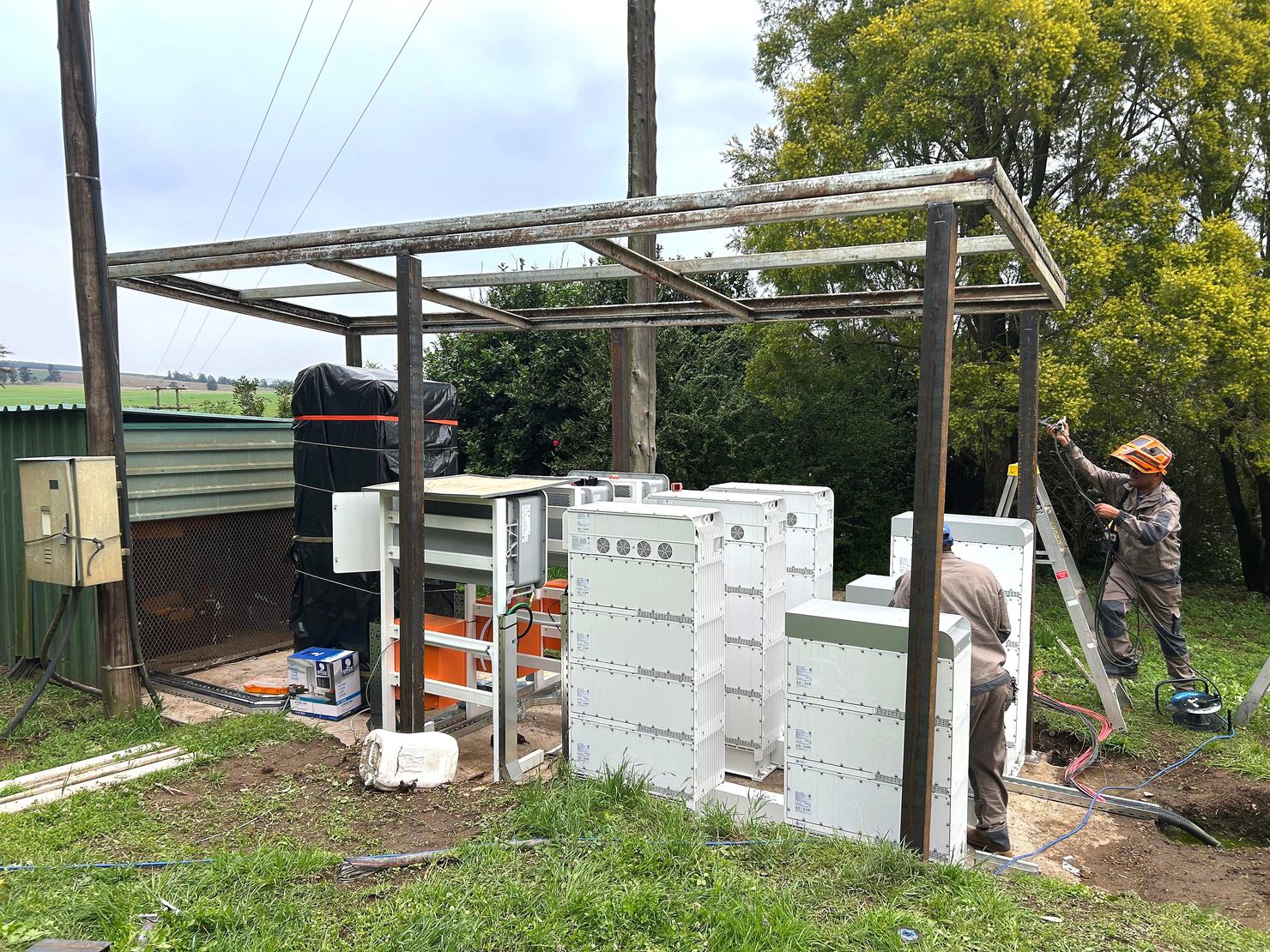 Install team erecting a steel shelter frame over Sigen Stack units at the GB Dairy site.