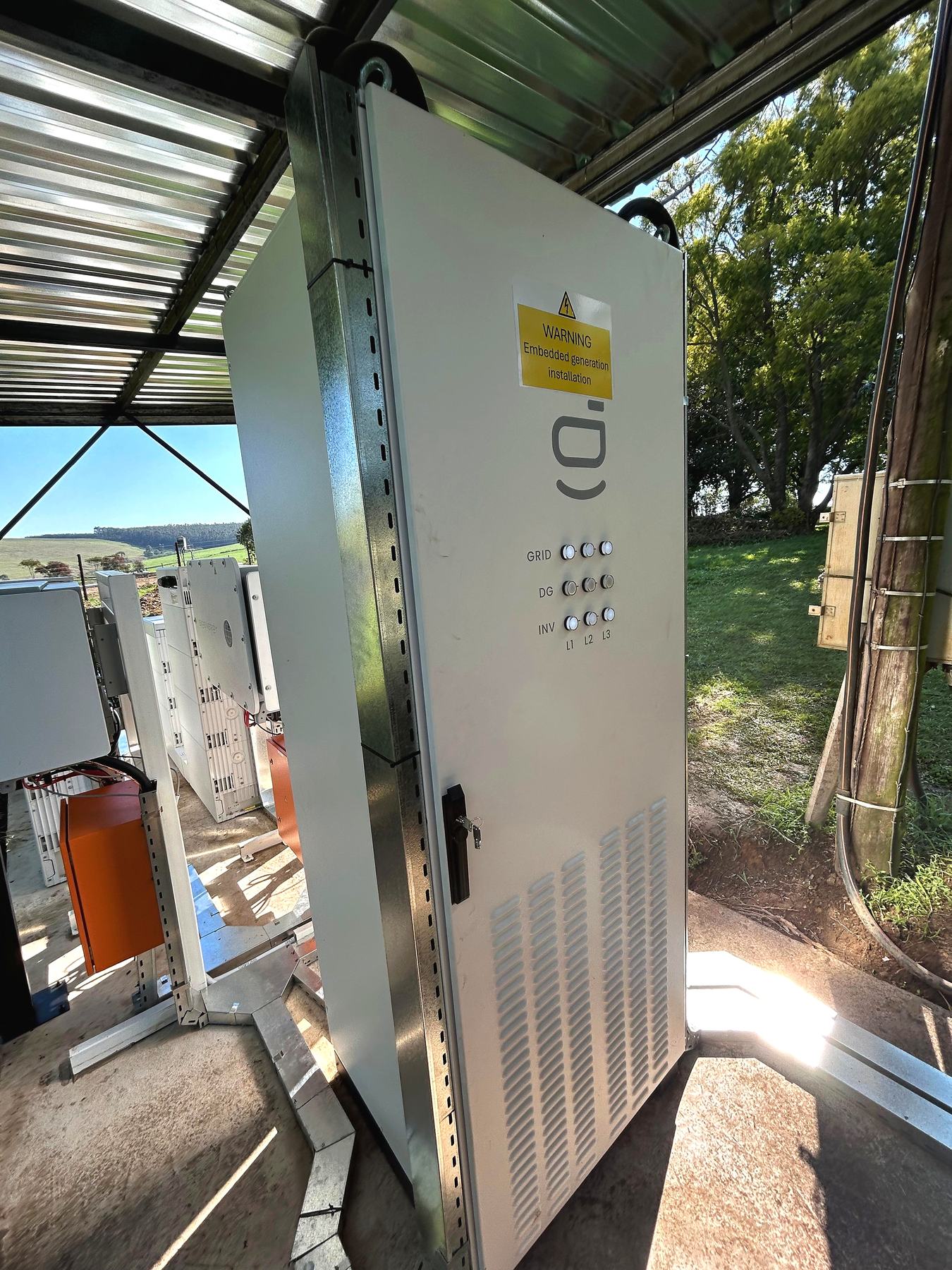 Deo Solar embedded-generation cabinet with GRID / DG / INV indicators under the steel shelter at GB Dairy.