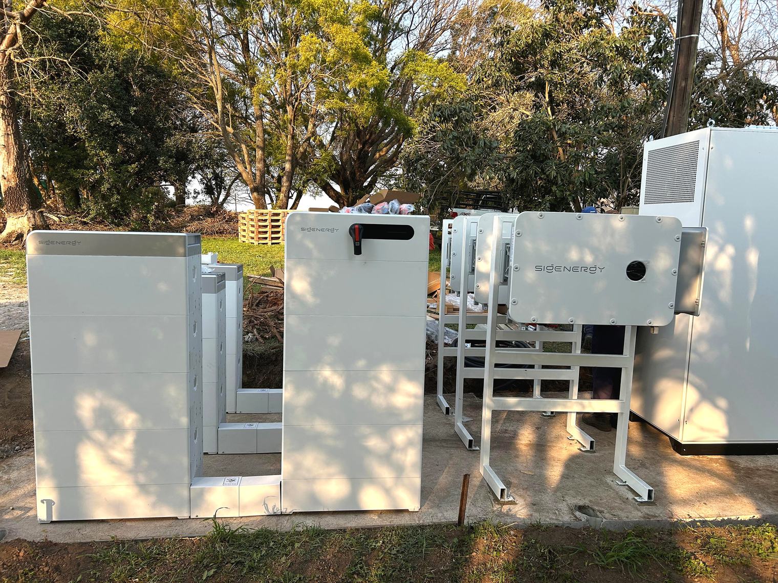 Outdoor GB Dairy Sigenergy C&I install: Sigen Stack battery modules and HYB inverters on a concrete pad.